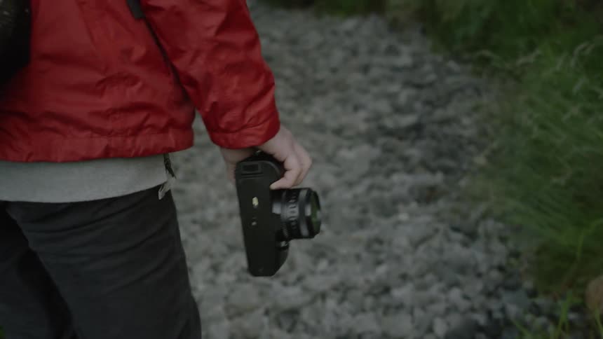 A person carries their camera on the trail