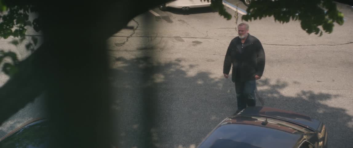 The man walks across the street below