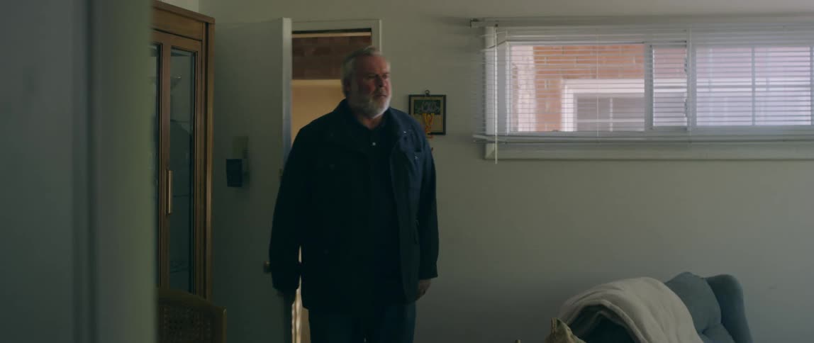 A man enters an apartment and starts to take of his coat