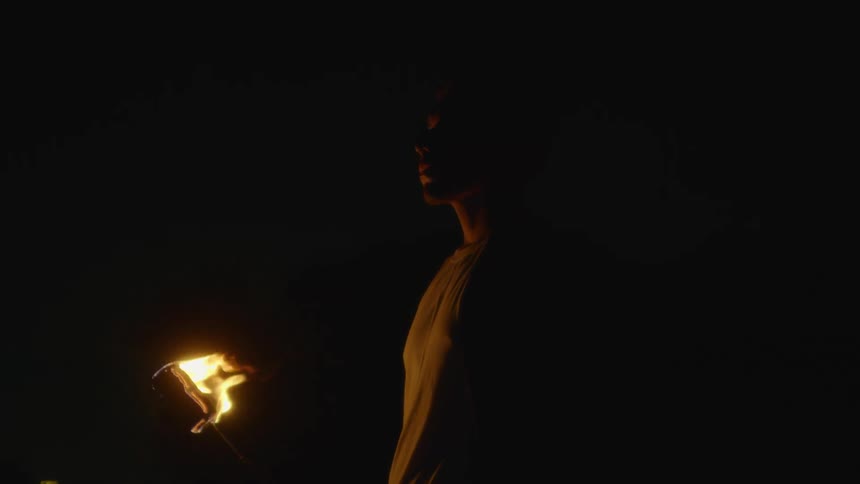 A man holds a torch outside at night