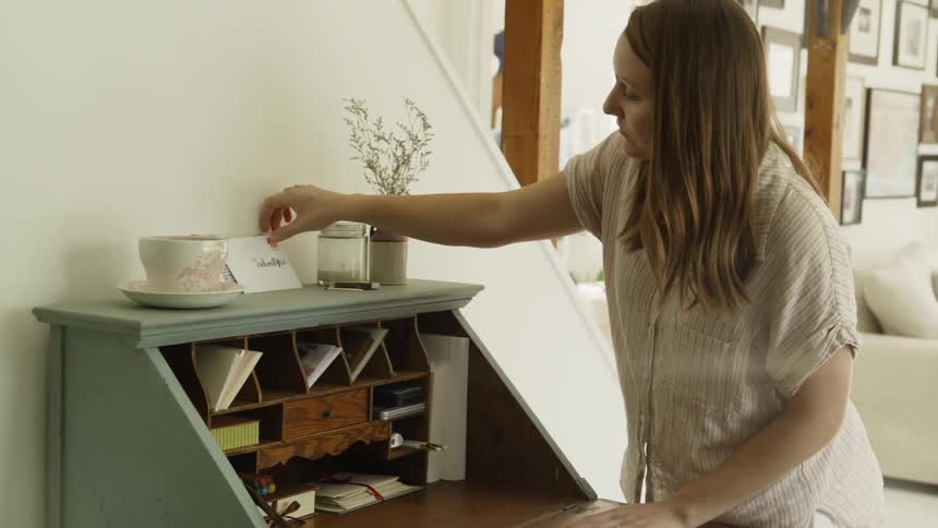 Woman organizes a small wooden desk and shuts the lid