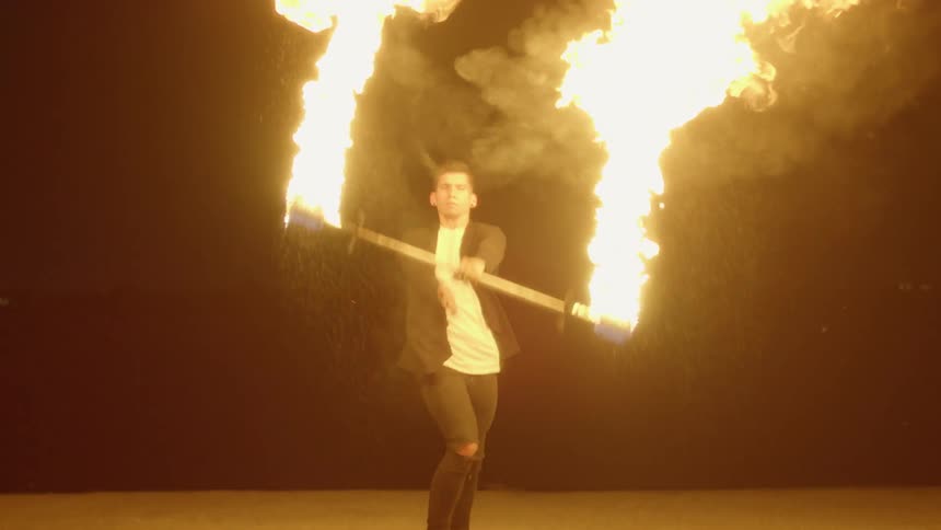 A man performs with a flaming baton at night
