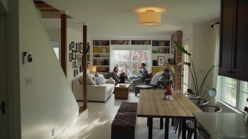Man and woman sit in the family room with a black dog