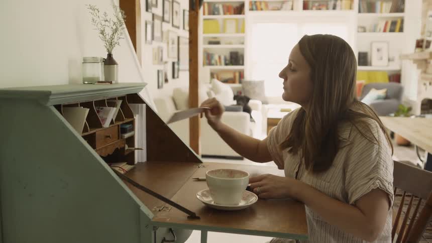 Woman sits at a desk and takes out an envelope