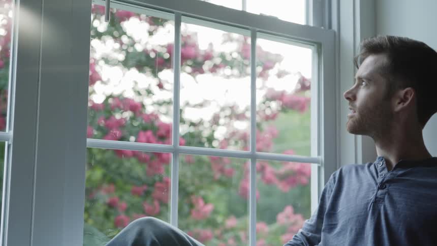 Man sits and looks out the window on a sunny day
