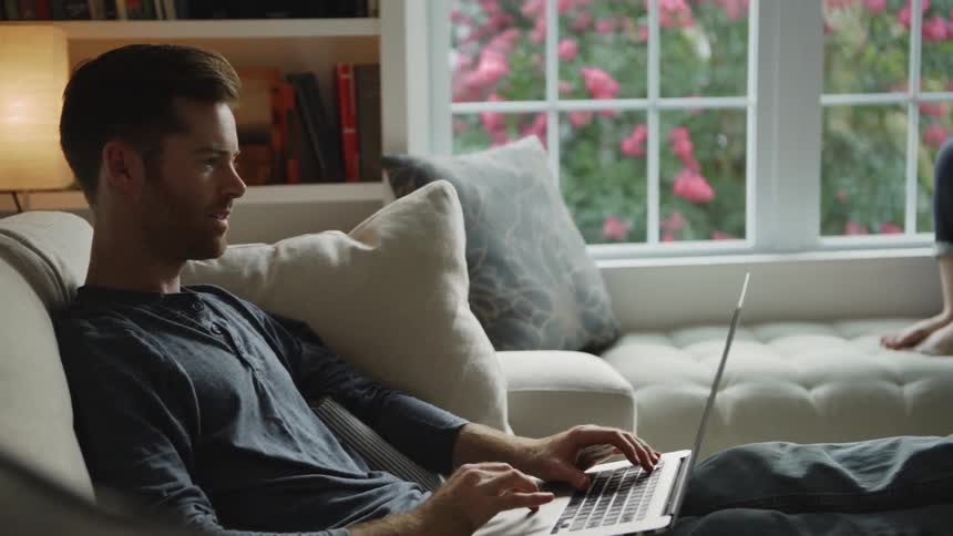 The woman smiles and talks with a man using a laptop