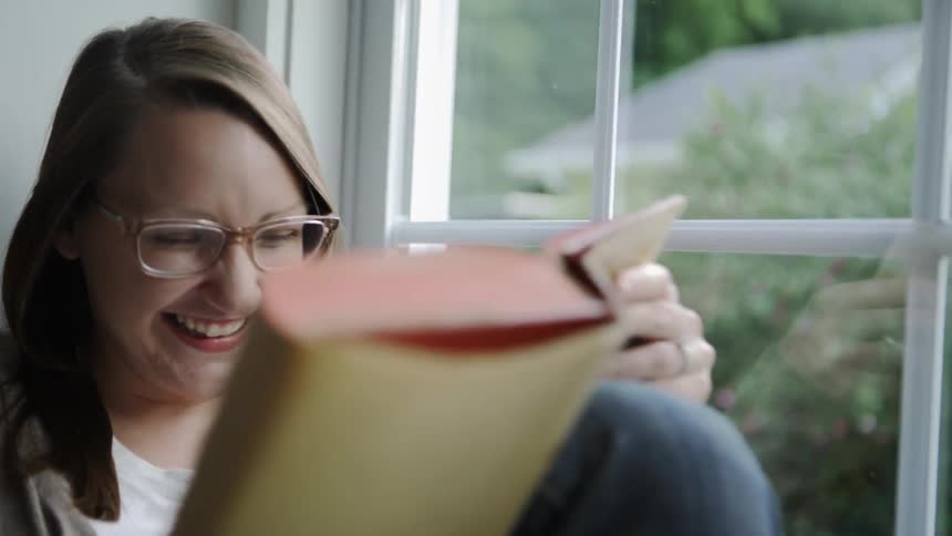 The woman laughs as she reads her book
