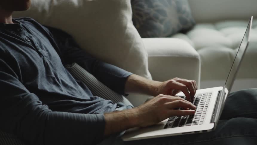 Woman smiles and reads while a man types on a laptop