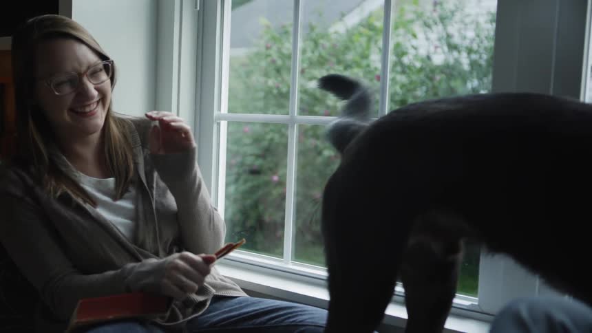 A dog's wagging tail hits a woman as the dog kisses a man