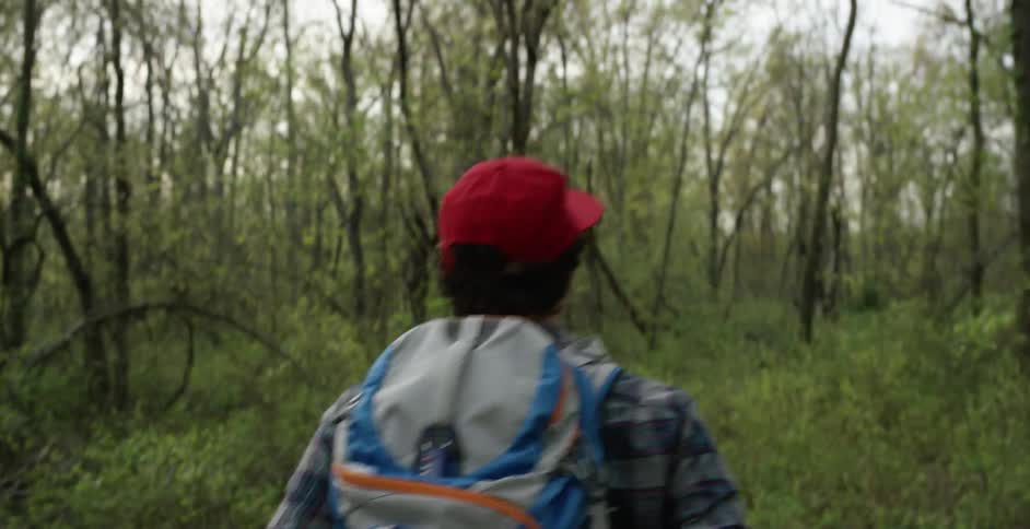 Man wearing a backpack walks through a forest