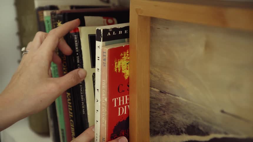 A woman looks through the books on a shelf