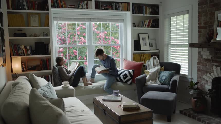 Man sits on a sofa with a woman and they both read their books