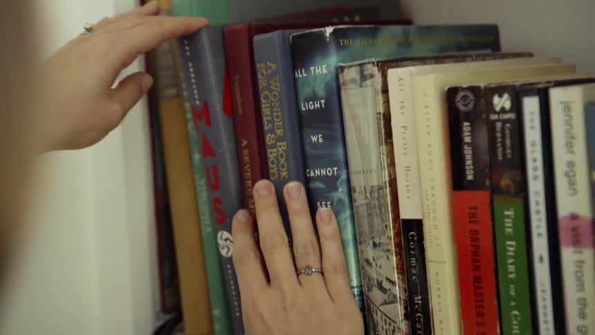 A woman looks at books on a shelf