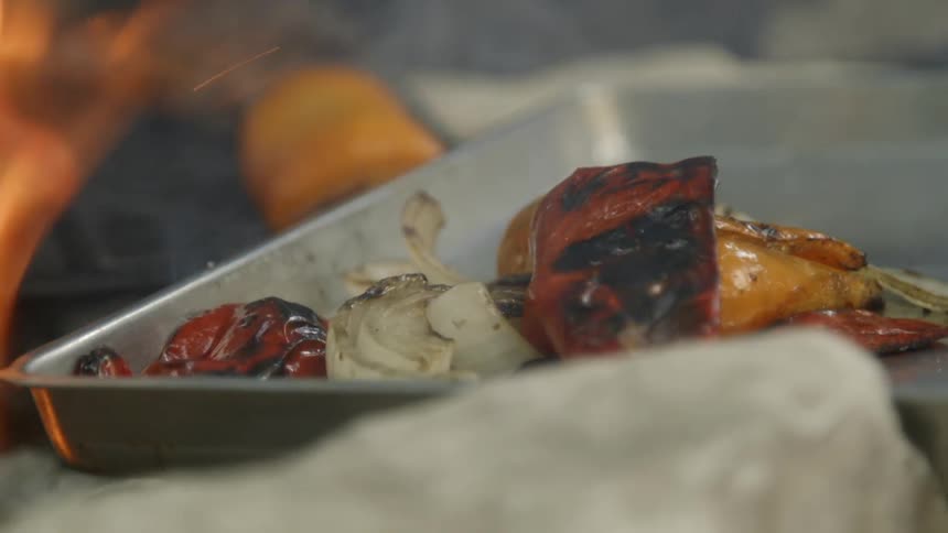 Tongs take vegetables off a grill and places them in a tray