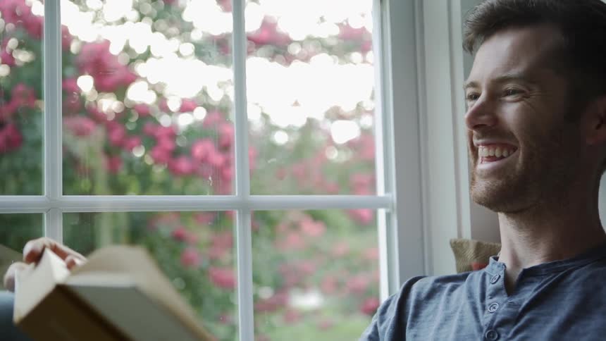 A man laughs as he reads his book