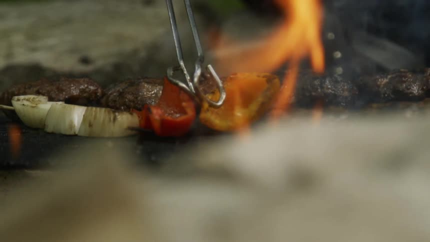 Tongs turn food over on a grill