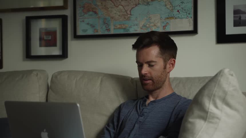 Man sits on the couch looking at a laptop
