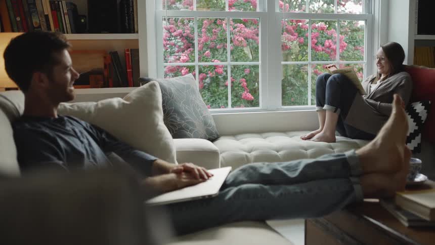 Man and woman sit in the living room smiling