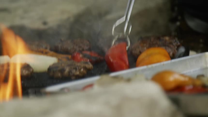 Person flips food over on a grill with tongs