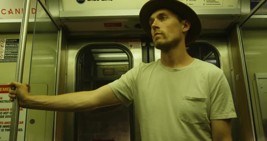 Man rides on the subway at night holding a pole