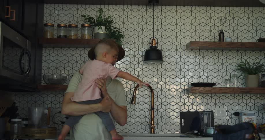A boy points at something while being held by his dad
