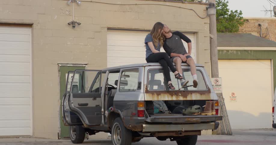 A man and woman cuddle while sitting on top of a truck
