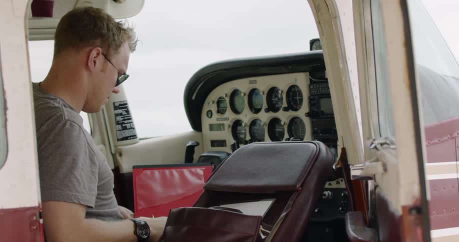 A pilot sits in a parked airplane