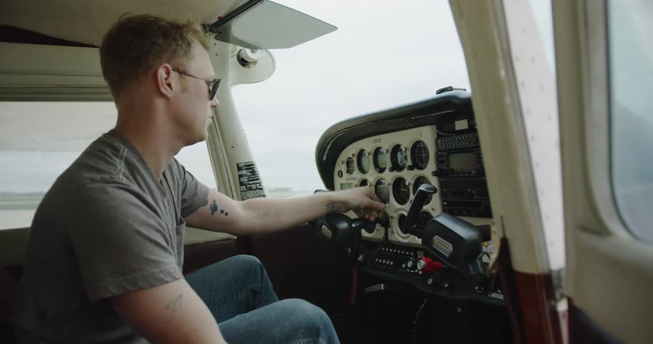 A man sits in the cockpit of a parked airplane