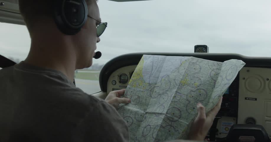 A man sits in a plane looking at a map on a cloudy day