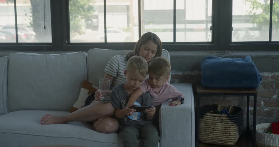 Woman sits on a couch with two boys