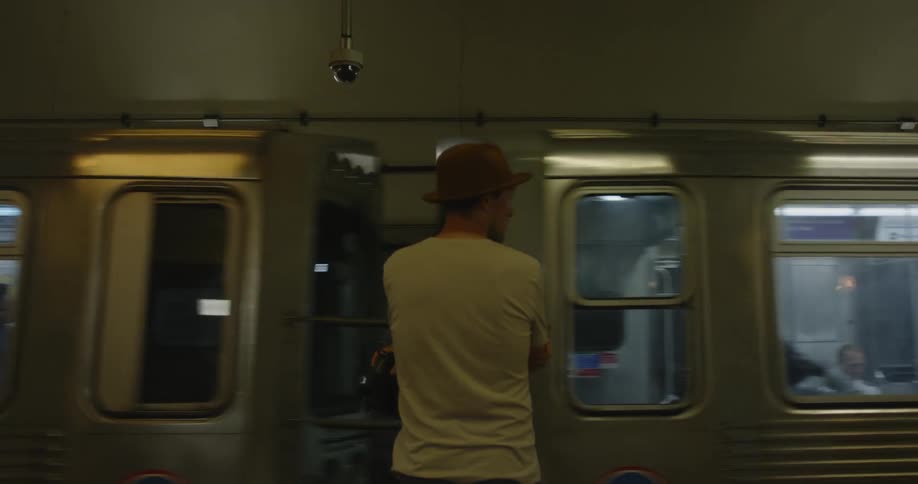 Man wearing a hat watches a train go by