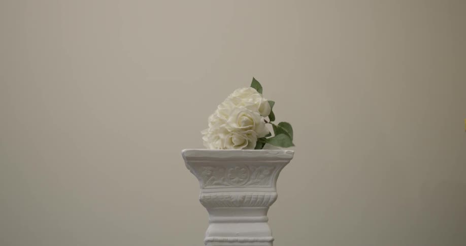 White flower falls onto a white pillar