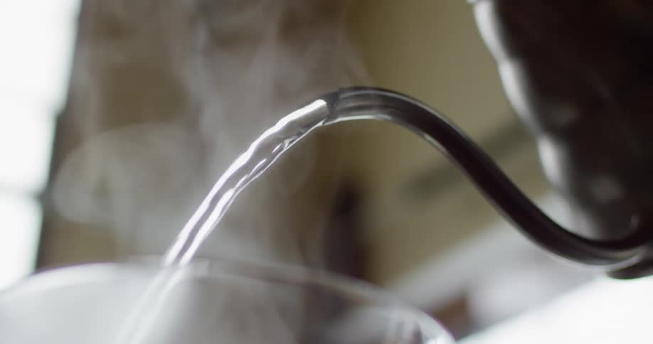 Hot, steaming water is poured from a kettle