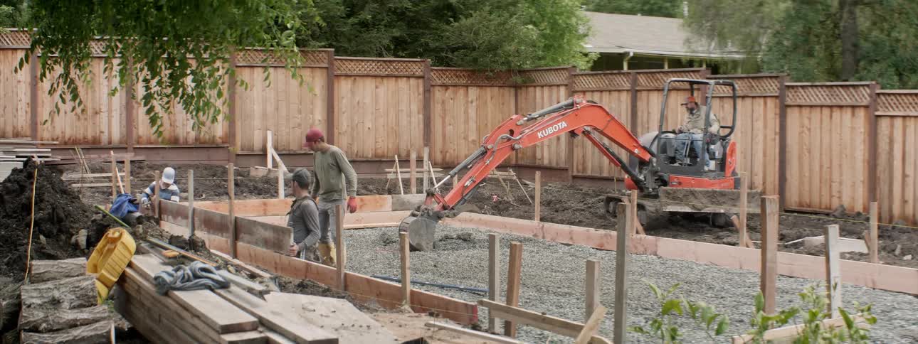 The construction vehicle is digging in the yard