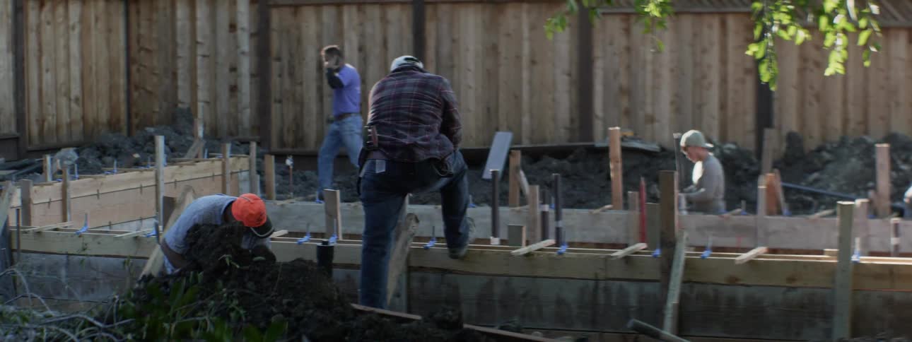 Men work at a construction site in a backyard