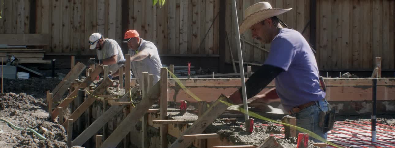 Workers lay concrete at a construction site