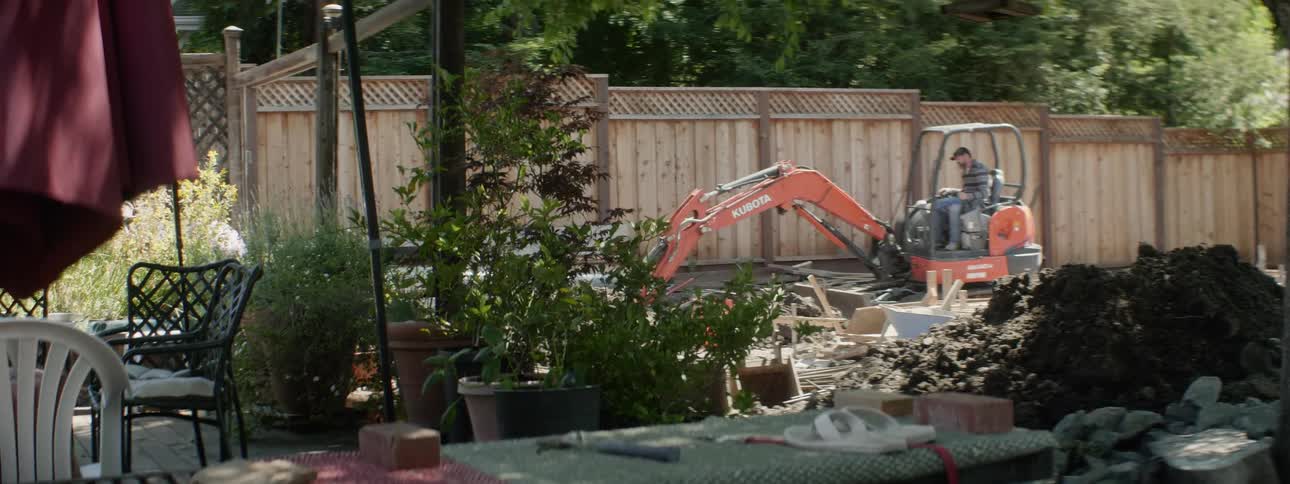 The construction vehicle digs all around the yard
