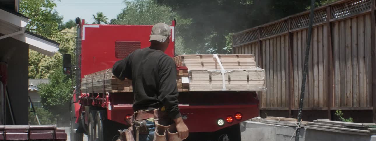 The large truck backs up with lumber in the construction site