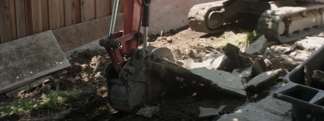 An excavator tears out concrete at a construction site