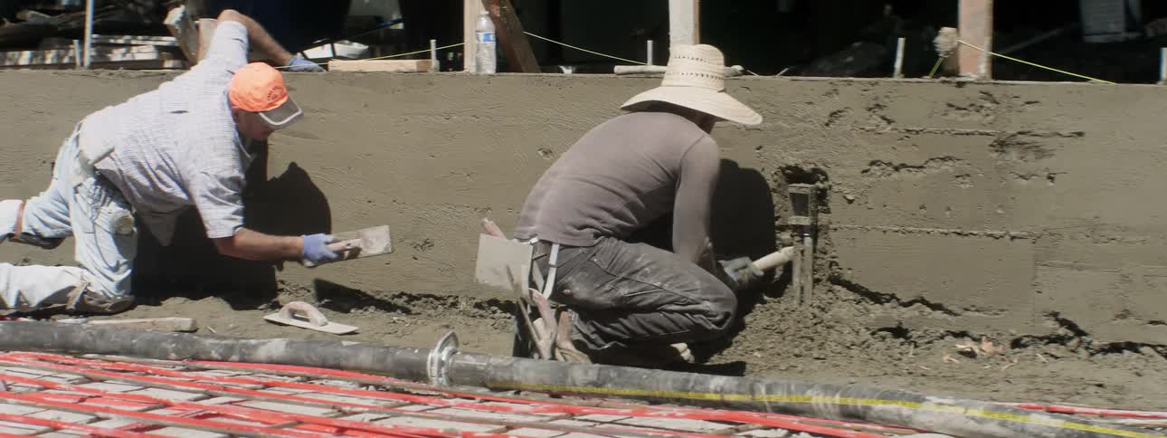 Workers lay concrete at a construction site