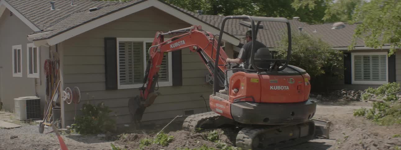 The construction vehicle is digging under the house