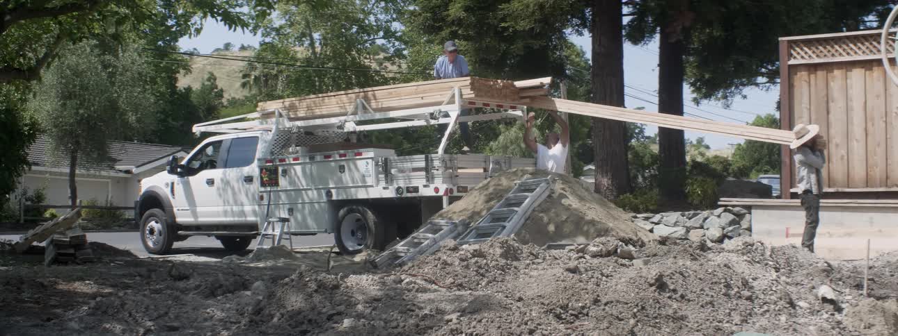 The construction workers are unloading lumber