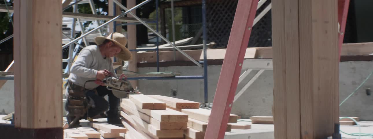 The construction worker cuts a plank of wood