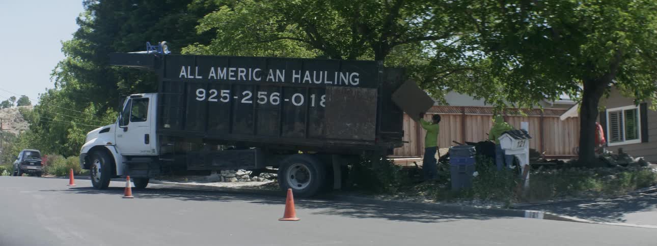 Men load trash into the back of a truck