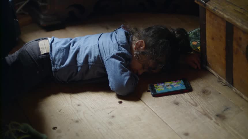 A young girl sleeps on a wood floor