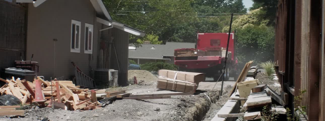 A large truck delivers wood at a construction site