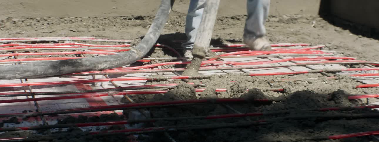The man is using a hose to spray cement