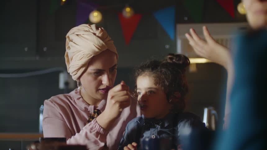A woman feeds a young girl cake at a party