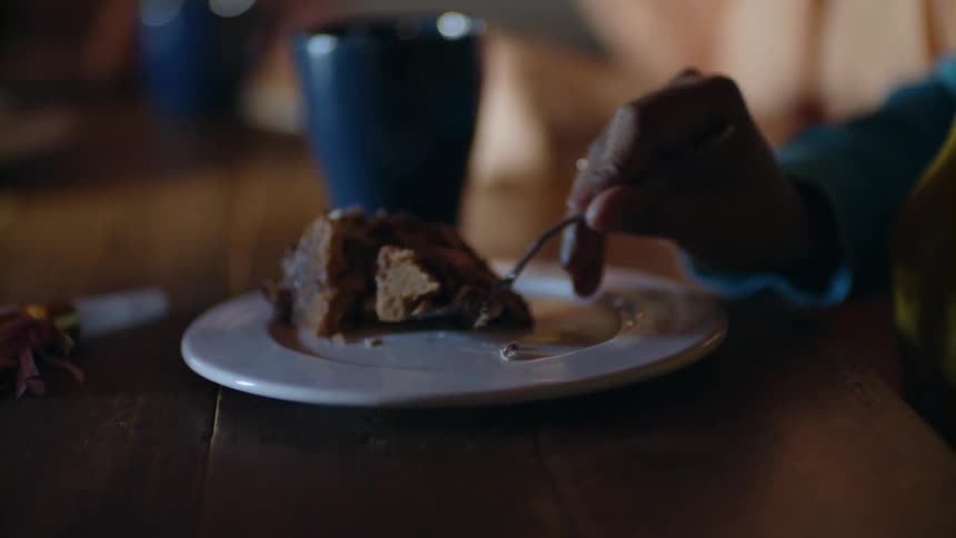 A woman sits at a table eating chocolate cake