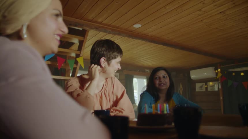 Women talk while gathered around a birthday cake